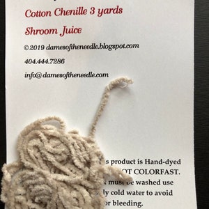 May include: A close-up of a cream-colored cotton chenille yarn, labeled "Shroom Juice" and 3 yards in length. The text on the card reads "Dames of the Needle - From the Cauldron".