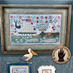 May include: A cross stitch pattern book titled "Seaworthy" featuring a nautical scene with a mermaid, a lighthouse, a sailboat, and a compass. The book includes three cross stitch charts.