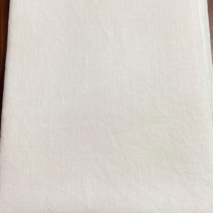 May include: A plain white linen fabric with a subtle texture. The fabric is smooth and has a slightly off-white color.