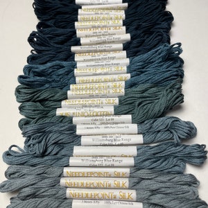 May include: An assortment of blue silk embroidery floss skeins. The skeins are labeled with the "Needlepoint Silk" brand and "Williamsburg Blue Range" color names. Each skein is 5 meters long and made of 100% Chinese silk.