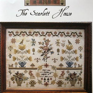 May include: A framed cross-stitch sampler titled "The Scarlett House" featuring floral and bird motifs, with the text "Mary Ann Farmer August 27th 1834". The sampler has a detailed design with a house illustration at the top.