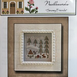 May include: A cross stitch pattern depicting a winter scene with a snowy forest, two rabbits, and a red cardinal. The pattern is titled "Frosty Forest" and is from Country Cottage Needlworks' "Snowy Friends" collection.