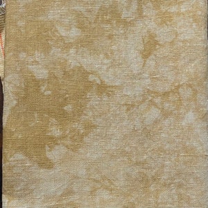 May include: Close-up of a textured fabric with a beige and off-white pattern. The fabric has a woven appearance, with visible threads creating a subtle, irregular design. The overall color palette is neutral, with variations in tone.