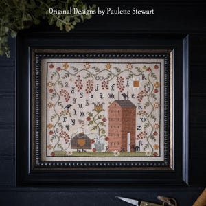 May include: A framed cross-stitch sampler with a house, flowers, and the alphabet. The sampler is titled "Tomato Sampler" and is by Plum Street Samplers. Original Designs by Paulette Stewart.
