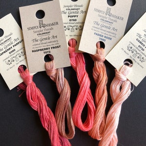 May include: Five spools of embroidery floss in shades of pink, red, and orange. The spools are labeled with the brand name "Simply Shaker" and the color names "Raspberry Frost", "Poppy", "Faded Rose", and "Cameo".