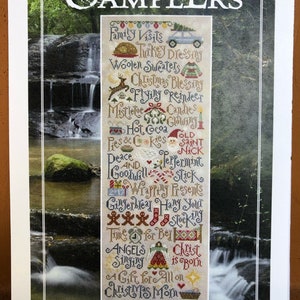 May include: A colorful cross-stitch sampler with a Christmas theme. The sampler features a variety of festive images and text, including a reindeer, a stocking, a gingerbread house, and the words "Peace and Goodwill".