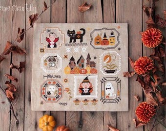 May include: A square beige fabric piece featuring detailed cross-stitch embroidery with Halloween motifs including a vampire, black cat, pumpkins, skulls, a haunted house, a witch, and a ghost. The text Madame Chantilly, Halloween, and 1489 are visible.