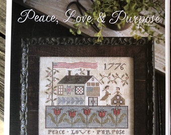 May include: A framed cross-stitch sampler with the text "Peace, Love & Purpose" and "1776". The sampler features a house, flags, and floral elements. The top of the image reads "PLUM STREET SAMPLERS".