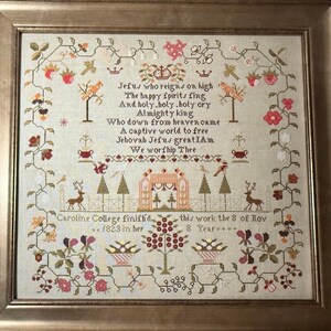 May include: A framed cross-stitch sampler with a beige background and colourful floral motifs. The sampler features a religious poem about Jesus and a date of completion: "1823".