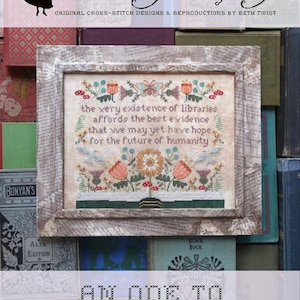 May include: A framed cross-stitch sampler with a floral design and the text "the very existence of libraries affords the best evidence that we may yet have hope for the future of humanity". The sampler is titled "An Ode to Libraries".