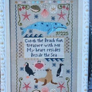 May include: Cross-stitch pattern featuring a whale, seagulls, a seal, and a starfish. The pattern includes the text "Comb the Beach for treasure with Me My heart resides Beside the Sea".