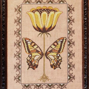 May include: A framed cross-stitch embroidery featuring a yellow flower with a butterfly on each side. The flower has a brown stem and roots. The background is a beige linen fabric with a brown and green border.