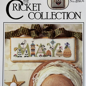 May include: Cross stitch pattern for the month of May, featuring a bird, bee, and flowers. The pattern is titled "May" and is part of "The Cricket Collection" by The Cross-Eyed Cricket. The pattern number is 32.4.