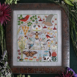 May include: A framed cross-stitch embroidery depicting a beehive with a variety of colorful flowers, birds, butterflies, and insects. The design is set against a light gray background.