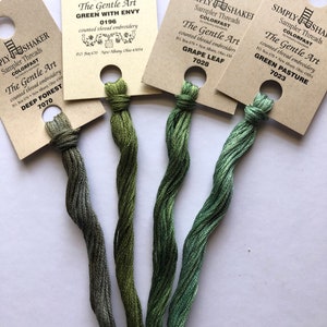 May include: Four spools of green embroidery floss, each with a different shade of green. The spools are labeled with the brand name "Simply Shaker" and the color name, such as "Deep Forest" and "Green Pasture".