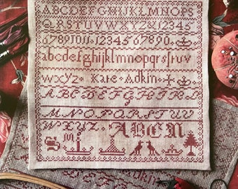 May include: A cross-stitch sampler with the text "Heartstring Samplery" and "KATE ADKIN (A FAITHFULLY REPRODUCED ANTIQUE SAMPLER)". The sampler features a variety of cross-stitched designs, including letters, numbers, and a small tree.