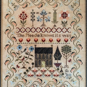 May include: Cross stitch pattern featuring a small house with a brown door, surrounded by flowers, trees, and birds. The text "The Needle knows its way" is stitched above the house.