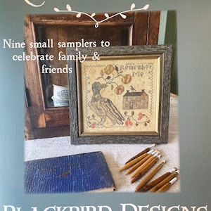 May include: A framed sampler with the text "Remember Me" and a bird design, displayed with a blue book and wooden tools. The image also includes the text "Nine small samplers to celebrate family & friends" and "Blackbird Designs".