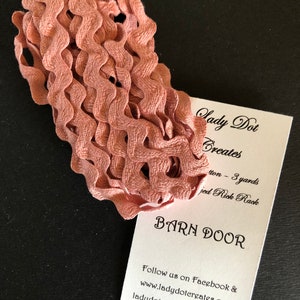 May include: A close-up of a pink, wavy, fabric trim. The trim is folded and stacked on a white card with the text "Lady Dot Creates" and "Barn Door". The card also includes the text "Follow us on Facebook & www.ladydotereates.com ladydotereates@gmail.com".