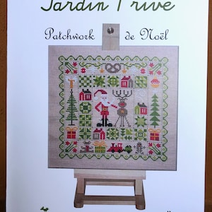 May include: A cross-stitch pattern featuring a Christmas scene with Santa Claus, a reindeer, and a train. The pattern is on a beige fabric with green, red, and white accents. The pattern is titled "Jardin Privé Patchwork de Noël" and is designed by Nathalie Cichon.