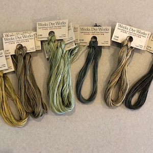 May include: Six spools of Weeks Dye Works embroidery floss in shades of green, brown, and yellow. The floss is labeled with the brand name, color number, and color name.