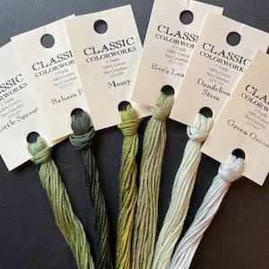 May include: Six spools of embroidery floss in shades of green and white. The spools are labeled with the brand name "Classic Colorworks" and the color name and number. The colors are "Little Sprout", "Balsam Fir", "Mossy", "Eve's Leaf", "Dandelion Stem", and "Green Onion".