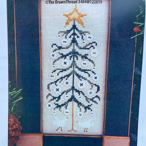 May include: A cross-stitch pattern featuring a stylized Christmas tree with white buttons for ornaments and two white birds at the base. The tree is green and brown with a gold star on top. The pattern is framed in a brown and blue frame with the text "The DrawnThread 3484W122819" at the top.