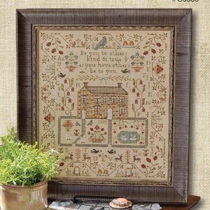 May include: A framed cross-stitch sampler featuring a central brick house, floral motifs, birds, and the alphabet. The text reads: Be you to others kind & true as you have others be to you. The year 2025 is stitched below the house in a dark wood frame.