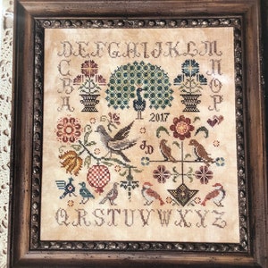 May include: A cross-stitch pattern featuring a vintage design with birds, flowers, and a peacock. The pattern includes the alphabet and the year 2017. The title "Vintage Birds" is at the top of the pattern.
