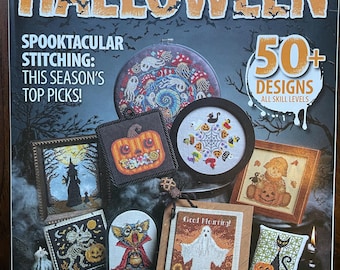 Op de afbeelding: De cover van het tijdschrift Just CrossStitch 2026 Special Collector's Issue Halloween bevat oranje tekst en diverse kruissteekontwerpen, waaronder een pompoen, een geest met de tekst Good Mourning, een zwarte kat, een heks en een skelet.