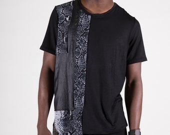 Puede incluir: Una camiseta negra con un estampado de piel de serpiente en el lado izquierdo y un panel de cuero negro. La camiseta tiene un corte holgado y cuello redondo.