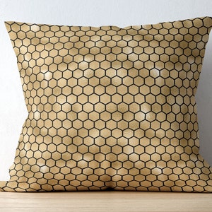 May include: A square throw pillow featuring a repeating geometric honeycomb pattern. The design consists of a metallic gold background with thin, crisp black lines forming the hexagonal grid across the entire surface of the pillow cover.