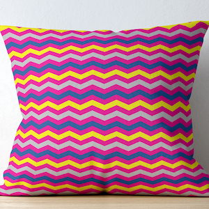 May include: A decorative pillow with a chevron pattern in pink, yellow, blue, and gray.