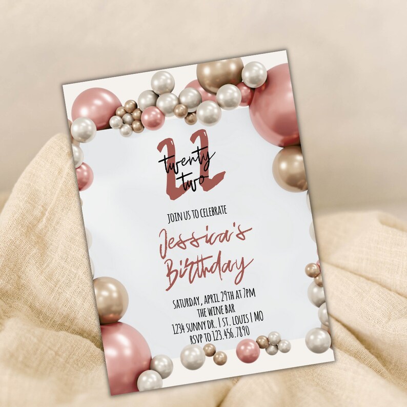 May include: A white invitation card with a pink and gold balloon border. The text on the card reads "Twenty Two" in a red script font, "Join us to celebrate Jessica's Birthday", "Saturday, April 29th at 7pm", "The Wine Bar", "1234 Sunny Dr. I St. Louis I MO", and "RSVP to 123.456.7890".