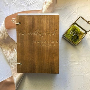 May include: A wooden box with a brown stain, engraved with the text "Our wedding cards Jason & Callie 05.05.2018".