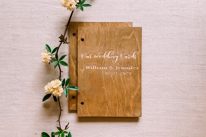 May include: A wooden box with a light brown stain. The box has two holes on the left side and is engraved with the text "Our wedding cards William & Jennifer 02.21.2020".