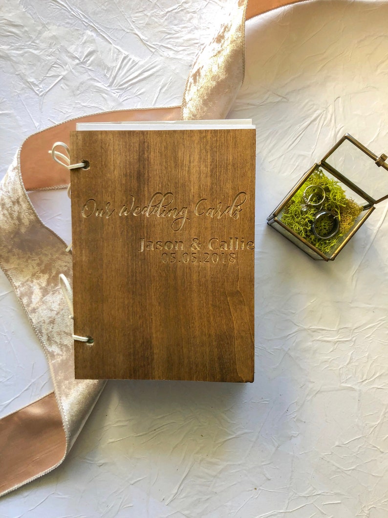 May include: A wooden box with a brown stain, engraved with the text "Our wedding cards Jason & Callie 05.05.2018".