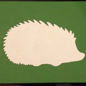 May include: A white silhouette of a hedgehog on a green canvas.
