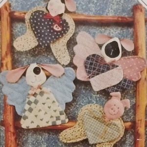 May include: A pattern for making fabric angel ornaments. The angels have heart-shaped bodies and wings, with animal faces. The pattern includes the text "HOLY COW & CO." and "FINDERS KEEPERS".