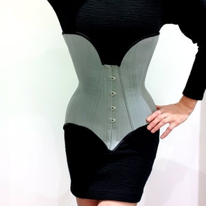 May include: A light grey corset with black trim and a row of silver buttons down the front.