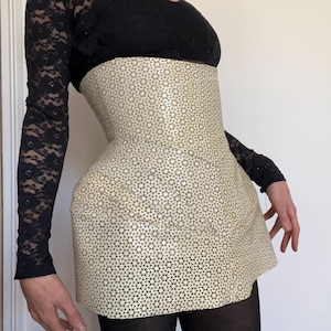 Op de afbeelding: Een witte rok met een geometrisch patroon. De rok is gemaakt van een glanzend materiaal en heeft een hoge taille.