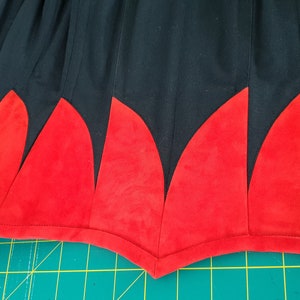 May include: A black skirt with a red suede trim. The trim is in a scalloped pattern.