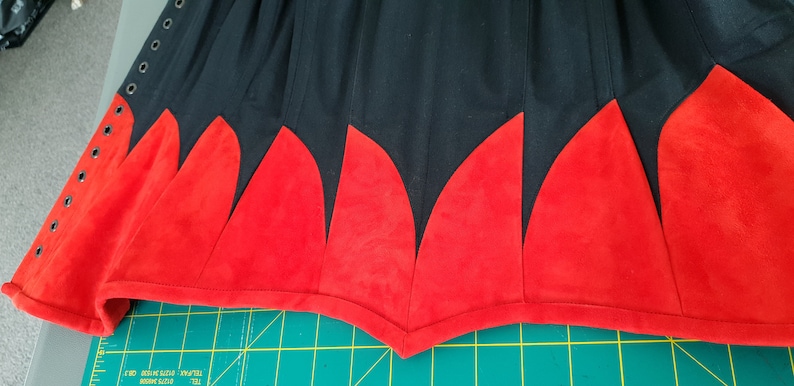 May include: A black skirt with a red suede trim. The trim is in a scalloped pattern.