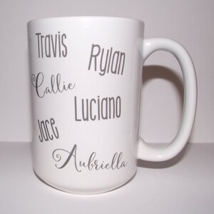 May include: White ceramic mug with a curved handle. The mug features the names "Travis", "Callie", "Jace", "Rylan", "Luciano", and "Aubriella" in grey lettering. The mug is a standard size for coffee or tea.