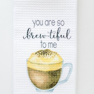 May include: White kitchen towel with a watercolor illustration of a cup of coffee and the text "You are so brew-tiful to me".