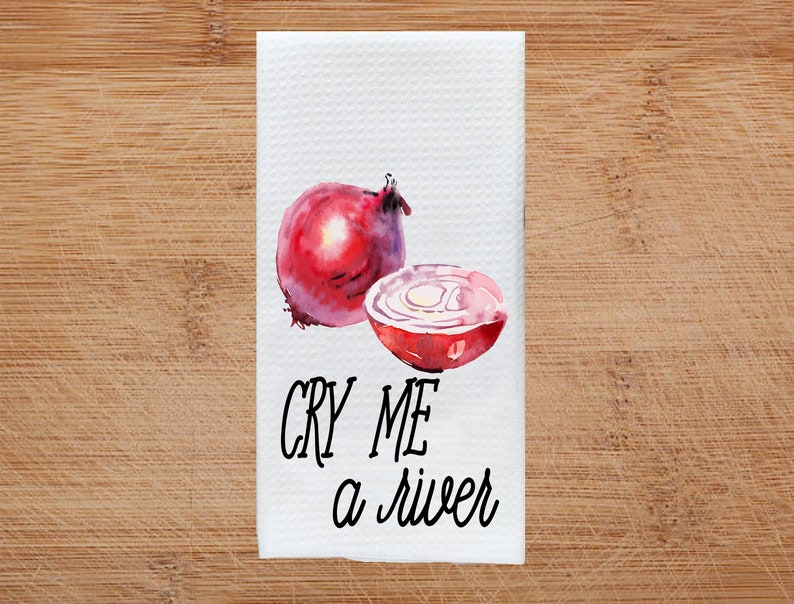 K&ouml;nnte beinhalten: Ein wei&szlig;es Geschirrtuch mit einer Aquarell-Illustration einer roten Zwiebel und dem Text "CRY ME A RIVER".