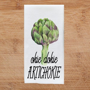 K&ouml;nnte beinhalten: Wei&szlig;es K&uuml;chentuch mit einer Aquarell-Illustration einer Artischocke und dem Text "okie dokie artichokie".