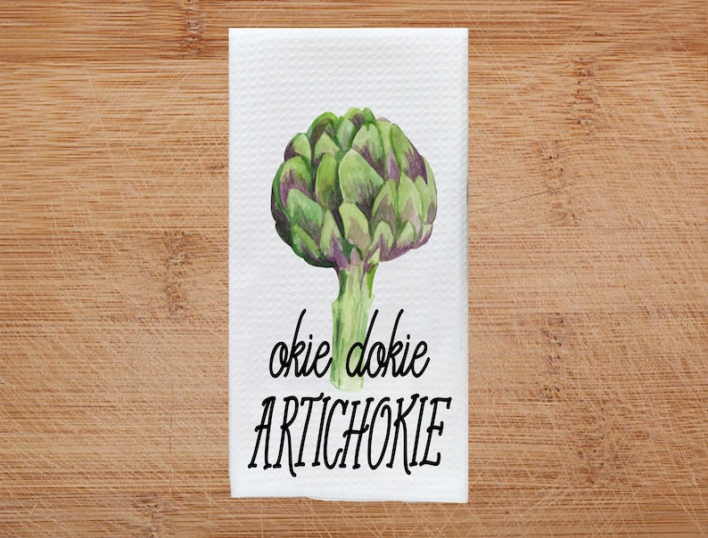 K&ouml;nnte beinhalten: Wei&szlig;es K&uuml;chentuch mit einer Aquarell-Illustration einer Artischocke und dem Text "okie dokie artichokie".