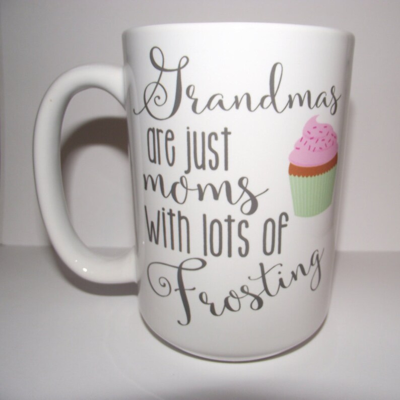 May include: White ceramic mug with a large handle. The mug features the text "Grandmas are just moms with lots of Frosting" in grey script. A cupcake graphic with pink icing and sprinkles is also on the mug.