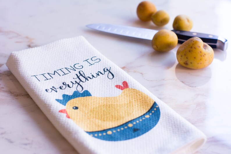 May include: White kitchen towel with a yellow chick illustration and the text "TIMING IS everything".